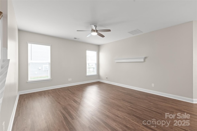 empty room featuring visible vents, baseboards, dark wood-type flooring, and a ceiling fan