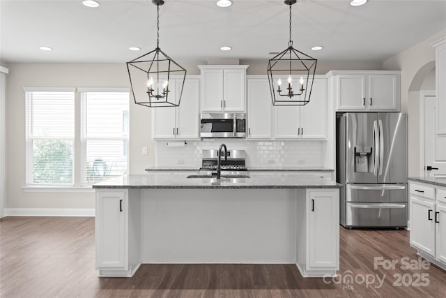 kitchen featuring dark wood-style floors, stone countertops, stainless steel appliances, white cabinetry, and a chandelier