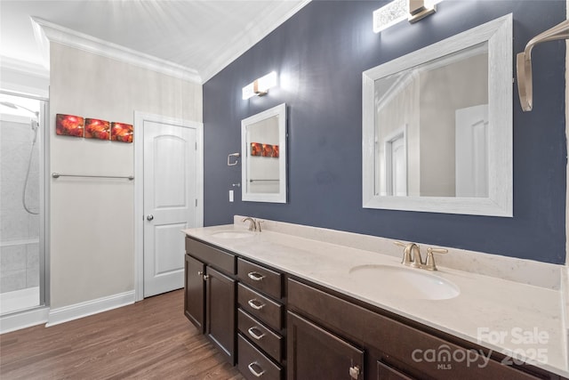 bathroom featuring crown molding, wood finished floors, double vanity, and a sink