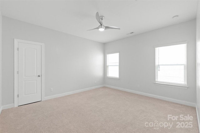 empty room with visible vents, baseboards, light colored carpet, and a ceiling fan