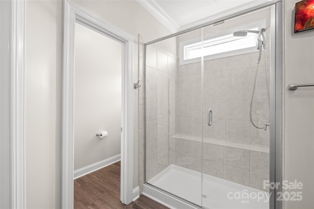 bathroom featuring a stall shower, crown molding, baseboards, and wood finished floors