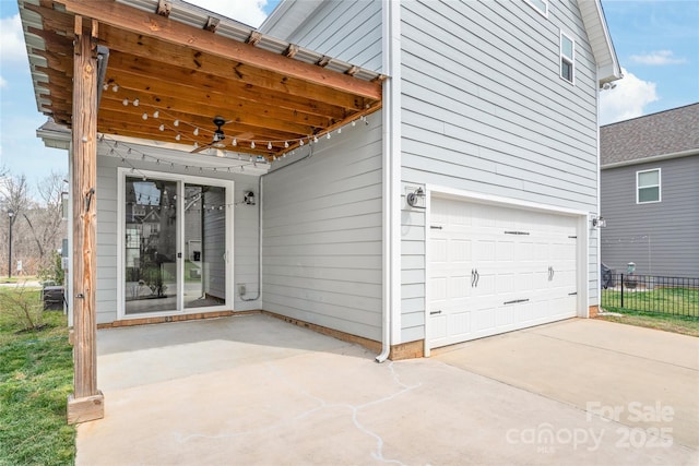 exterior space featuring an attached garage, fence, and ceiling fan