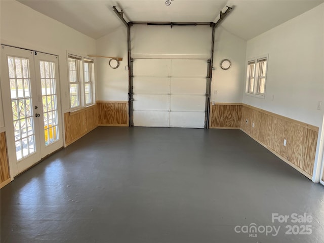 garage with french doors, a wainscoted wall, and wood walls