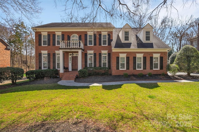 view of front of home featuring brick siding, a balcony, and a front lawn