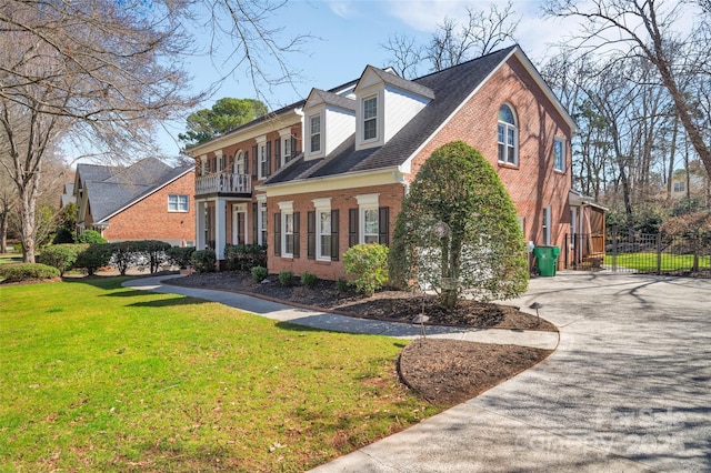 view of property exterior featuring fence, a lawn, brick siding, and driveway