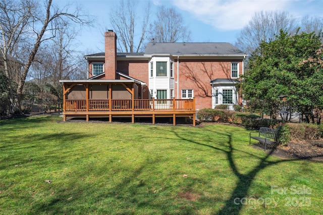 rear view of house featuring a deck, a yard, and a chimney