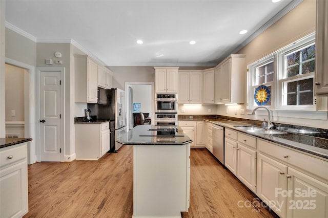 kitchen featuring a center island, crown molding, appliances with stainless steel finishes, light wood-style floors, and a sink