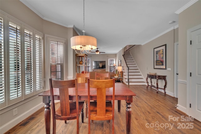 dining space with stairway, wood finished floors, visible vents, baseboards, and crown molding