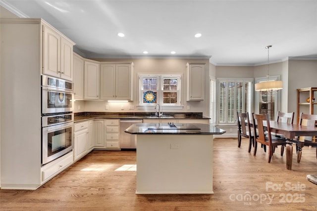 kitchen with light wood finished floors, a kitchen island, recessed lighting, appliances with stainless steel finishes, and hanging light fixtures