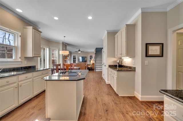 kitchen featuring a sink, a kitchen island, black electric cooktop, and ornamental molding