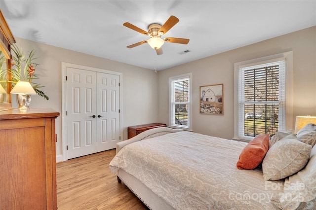 bedroom with visible vents, a closet, light wood-style flooring, and a ceiling fan