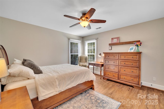 bedroom with ceiling fan, light wood-style floors, visible vents, and baseboards