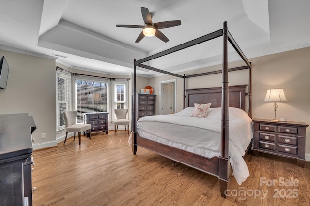 bedroom with visible vents, crown molding, a tray ceiling, and wood finished floors