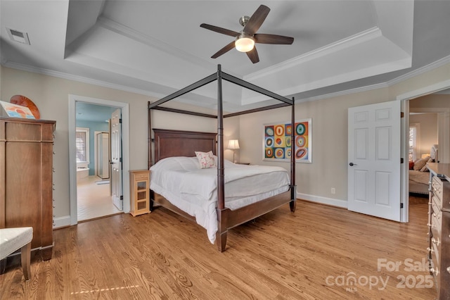 bedroom with a raised ceiling, ornamental molding, visible vents, and light wood-type flooring