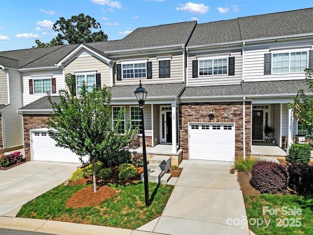 multi unit property with stone siding, driveway, and a shingled roof