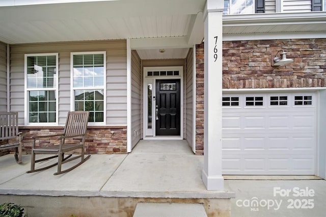 property entrance featuring a garage, covered porch, and stone siding