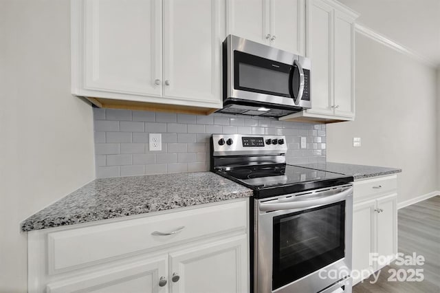 kitchen featuring backsplash, white cabinets, appliances with stainless steel finishes, and light stone countertops