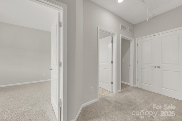 corridor with attic access, carpet, baseboards, and visible vents