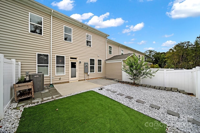 back of property with a patio area, a fenced backyard, a lawn, and central AC