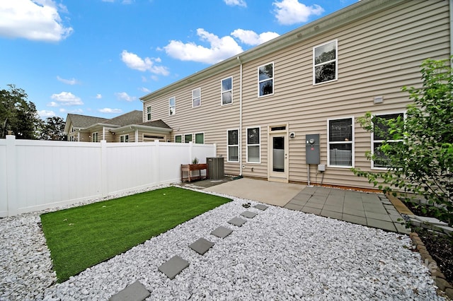 rear view of property with a yard, a patio, central AC, and fence