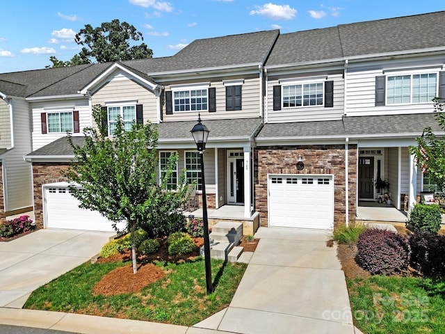 townhome / multi-family property featuring concrete driveway, stone siding, and a shingled roof