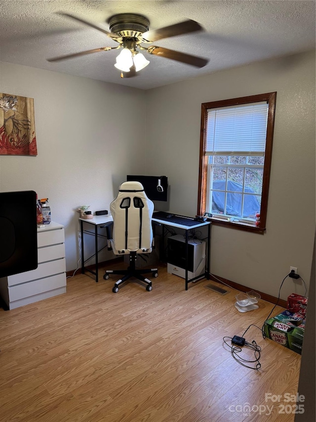 office area with a textured ceiling, a ceiling fan, baseboards, and wood finished floors