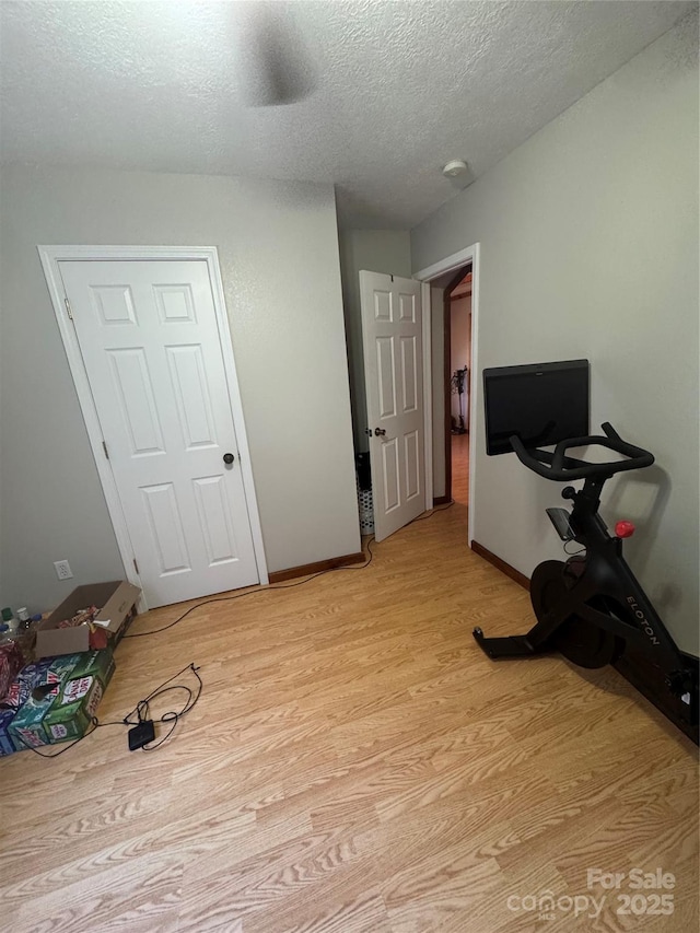 interior space with light wood-style floors, baseboards, and a textured ceiling