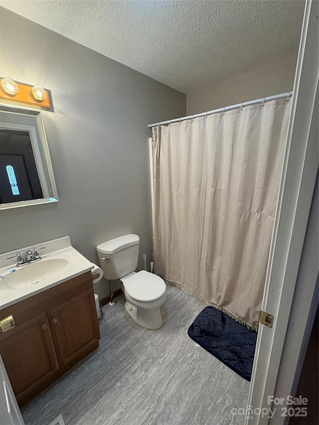 full bath featuring vanity, wood finished floors, a textured ceiling, curtained shower, and toilet