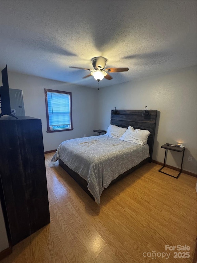 bedroom featuring a textured ceiling, light wood-style floors, and a ceiling fan