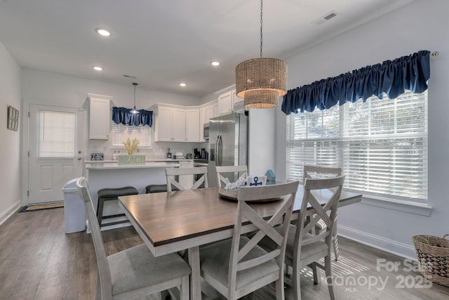 dining area featuring visible vents, wood finished floors, baseboards, and a chandelier