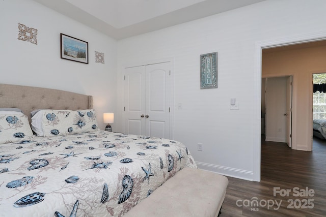 bedroom with a closet, dark wood-style floors, and baseboards