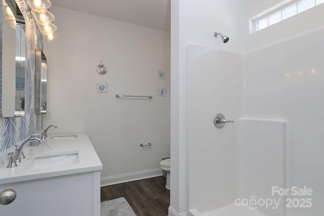 bathroom with wood finished floors, toilet, a shower, and a sink