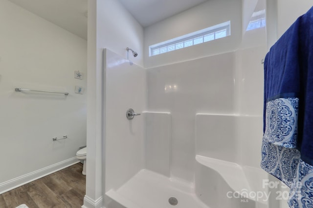 full bathroom featuring wood finished floors, toilet, a shower, and baseboards