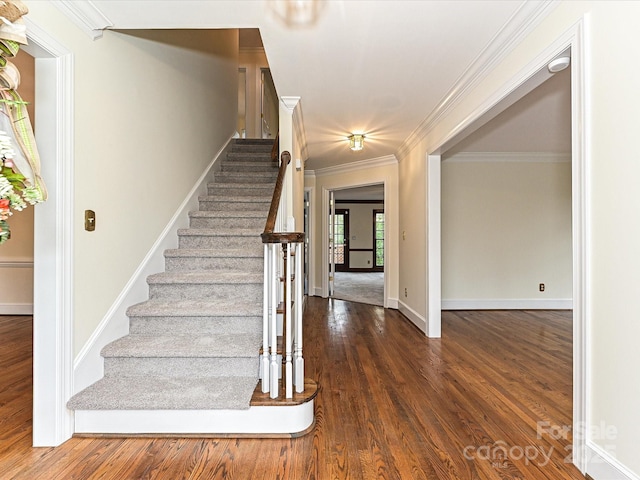 stairs with crown molding, wood finished floors, and baseboards