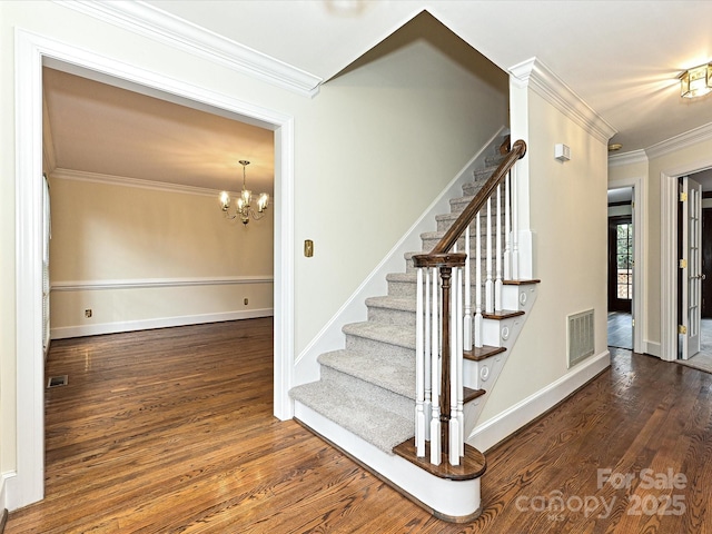 staircase featuring visible vents, wood finished floors, a notable chandelier, and ornamental molding