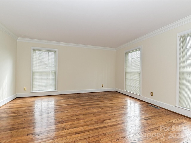 spare room featuring visible vents, baseboards, wood finished floors, and ornamental molding