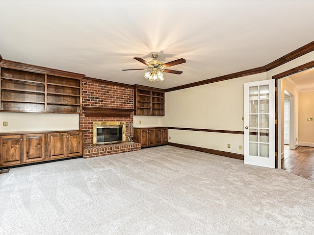 unfurnished living room featuring baseboards, crown molding, a ceiling fan, and carpet floors