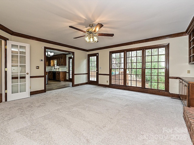 unfurnished living room with carpet flooring, baseboards, crown molding, and ceiling fan