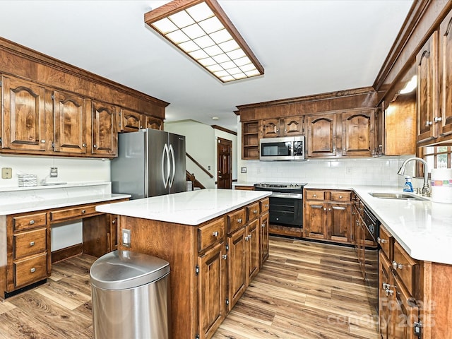 kitchen with light wood-type flooring, a sink, appliances with stainless steel finishes, tasteful backsplash, and a center island