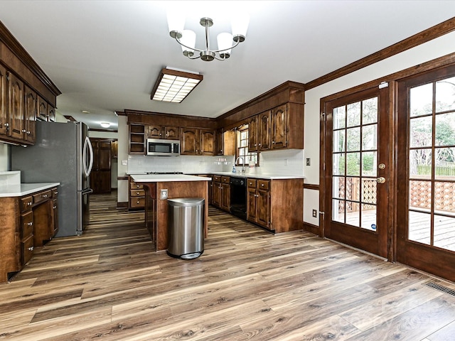 kitchen featuring tasteful backsplash, wood finished floors, a center island, stainless steel appliances, and an inviting chandelier