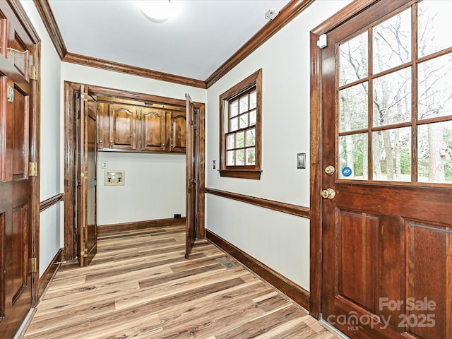 interior space featuring baseboards, ornamental molding, and light wood finished floors