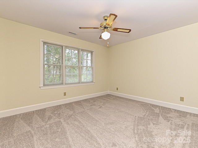 carpeted spare room with visible vents, baseboards, and a ceiling fan