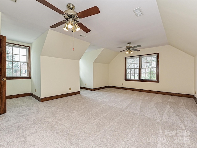 additional living space with light colored carpet, visible vents, a wealth of natural light, and ceiling fan