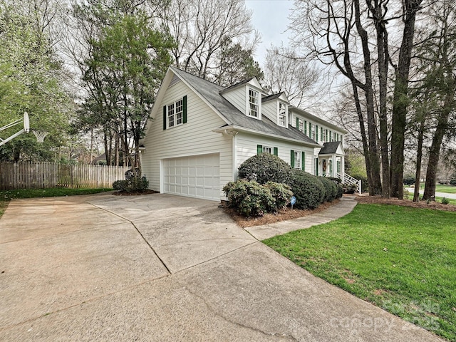 view of side of property featuring driveway, fence, a yard, roof with shingles, and an attached garage