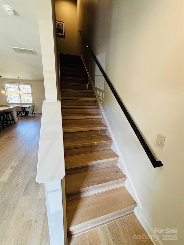 stairs with visible vents, baseboards, and wood finished floors