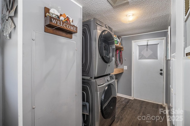 laundry room featuring visible vents, a textured ceiling, wood finished floors, stacked washer / dryer, and laundry area