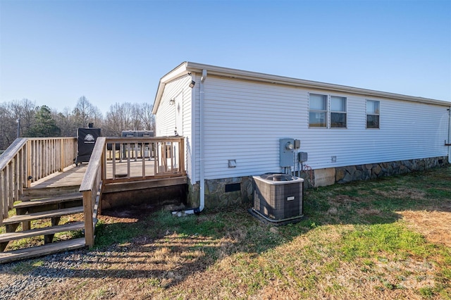 rear view of property featuring crawl space, a lawn, cooling unit, and a deck