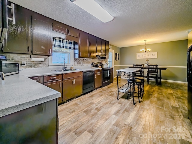 kitchen with a sink, light wood finished floors, light countertops, tasteful backsplash, and black appliances