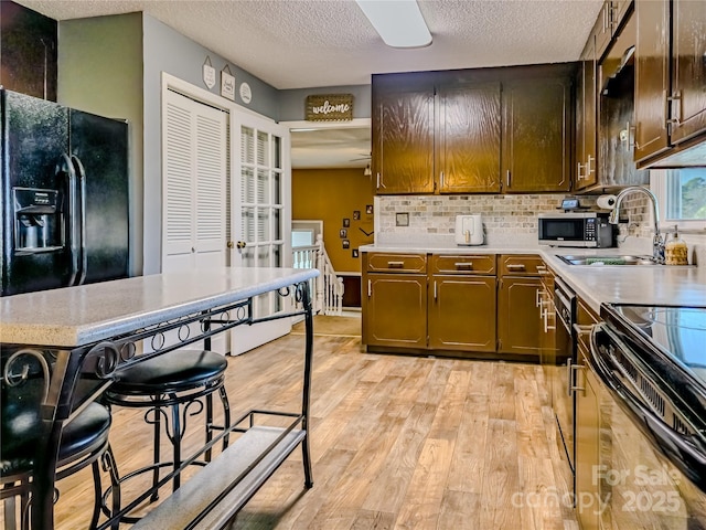 kitchen featuring a sink, light wood-style flooring, a textured ceiling, and light countertops