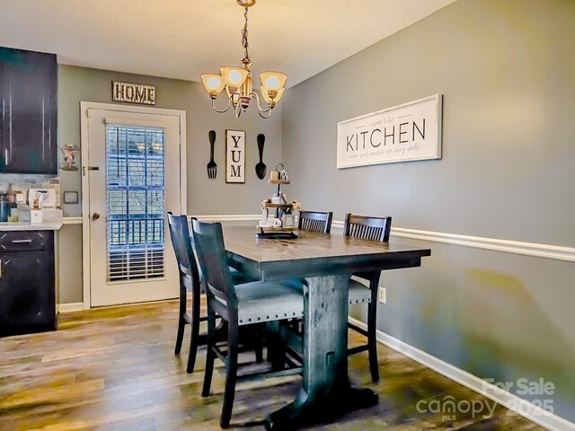 dining space featuring baseboards, a chandelier, and light wood-type flooring